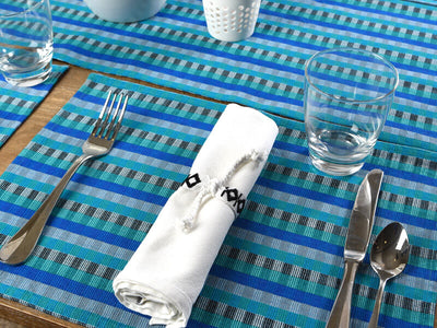 Blue cuadritos placemat with white Celebration napkin and napkin tie